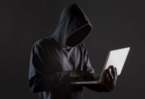 side view of male hacker with gloves and laptop 850x580 1